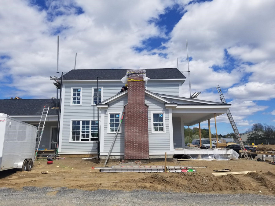 Beautiful construction of The Baldwin model home showing the spacious front porch and chimney